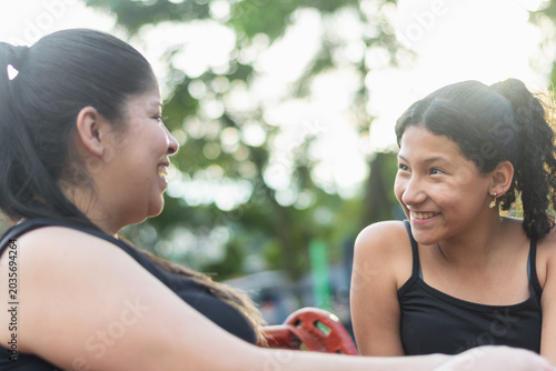 Young Latina mother and smiling daughter enjoying an honest conversation together in the park