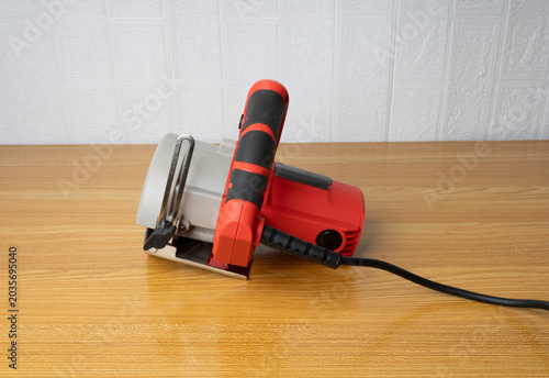red electric saw on wooden table.