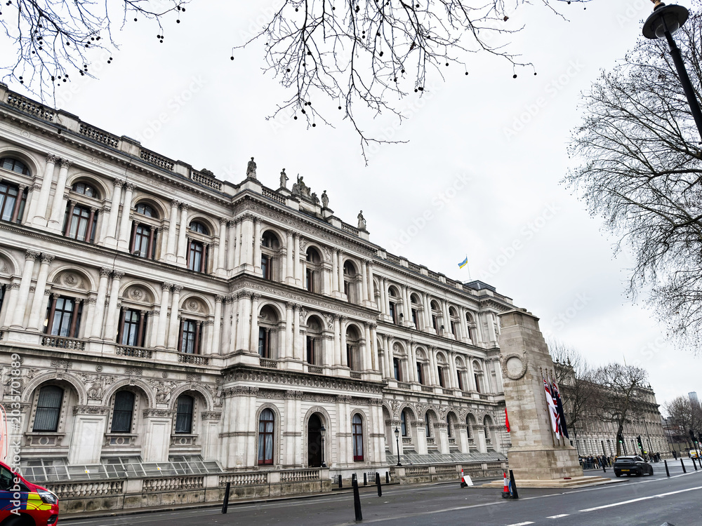 Naklejka premium Historic Foreign, Commonwealth and Development Office government building facade on wide street in central London UK with memorial column