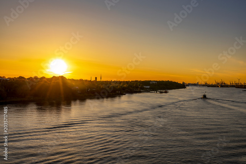 Dawn breaks over the Elbe River, illuminating the path to Hamburg with a golden glow.