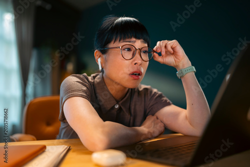 Bilde på lerret Focused remote worker concentrating on a laptop screen during an online work session in a modern home office environment