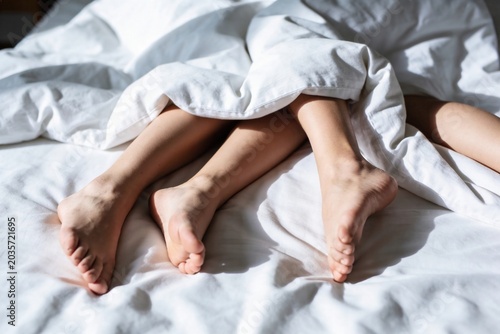 The Intertwined Legs,, Subconscious Clinging, Comfortable Morning Scene with Bare Feet Under White Blankets