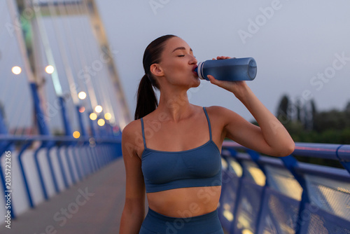 Cuadro en lienzo Young caucasian female athlete drinking water during outdoor cardio training