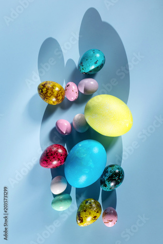 Easter still life with multicolored eggs, light, and shadows. View from above.