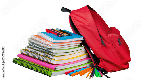 Isolated red backpack with a tall stack of colorful spiral notebooks and school supplies