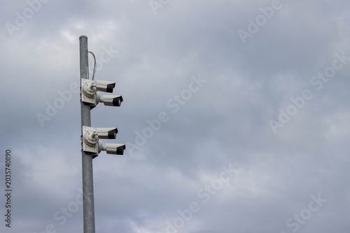 Foto Security camera system mounted on a tall metal pole against a cloudy sky, featur