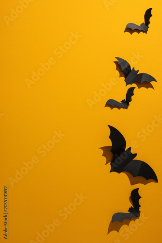 Halloween paper bat vertical decoration on bright orange background with dramatic shadow