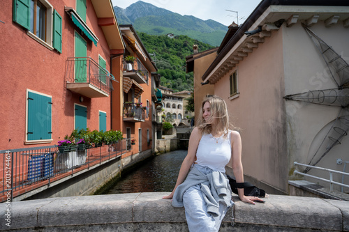 young woman sitting in a narrow colorful street near Lake Garda, Italy.