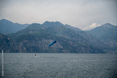 Kitesurfer riding on Lake Garda with mountain panorama in Italy.