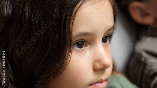 Fényképezés Young girl with dark brown hair and eyes looking away with a thoughtful, innocen