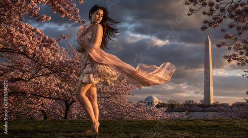 casually elegant modern woman standing among cherry trees in full blossom Washington DC in late afternoon on a windy day