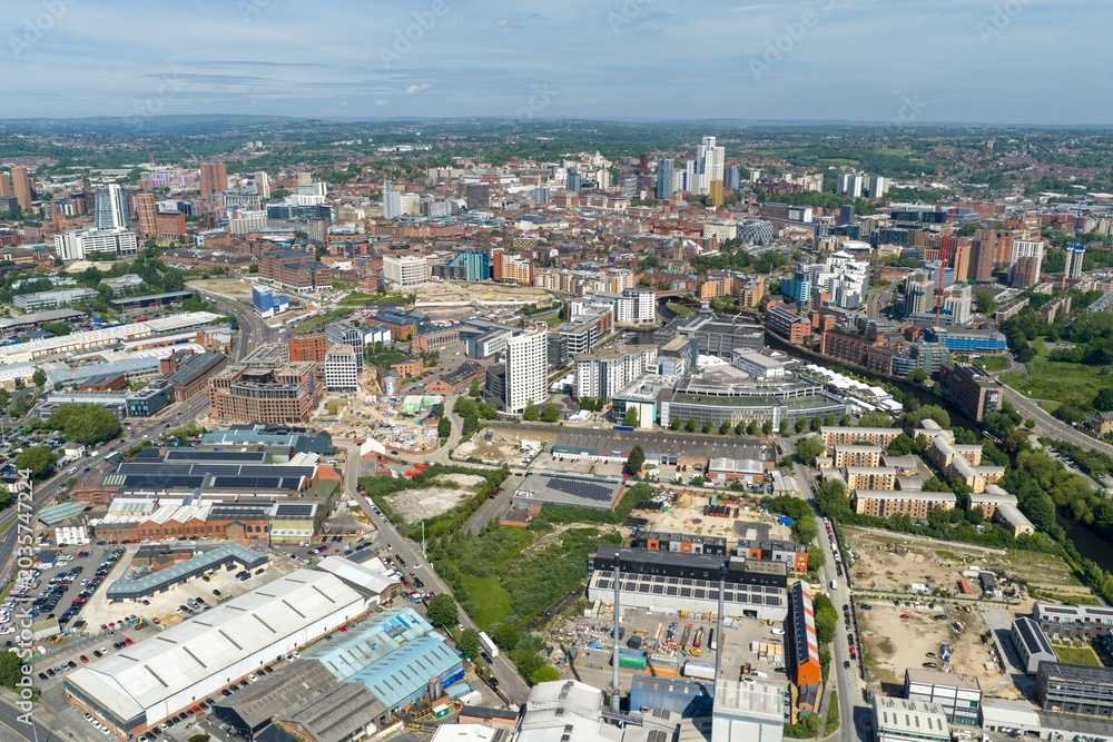 Obraz premium Detailed aerial drone view of Leeds city centre in West Yorkshire UK showing modern skyscrapers commercial districts and urban redevelopment beneath a bright blue sky in the summer time