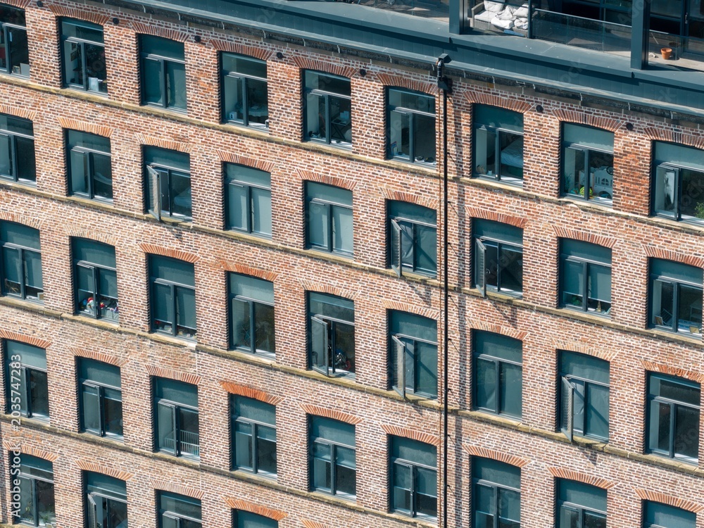 Obraz premium Close up aerial drone photograph of a modern brick apartment building facade in Leeds West Yorkshire UK showing geometric window patterns and urban residential architecture on the converted factory