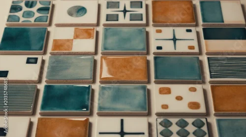 Panel kuchenny z motywem Assorted ceramic tiles show different abstract geometric patterns in shades of teal orange white. Square and rectangle shapes form surface textures. Modern wall decor for home design.