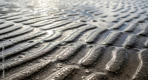 Close-up of rippled sand and water patterns on a beach at low tide