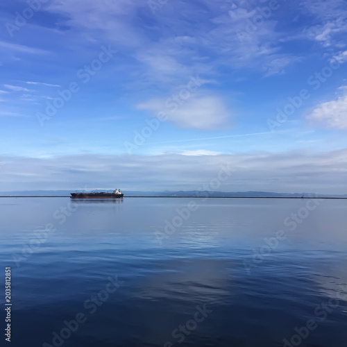 water with sunny cloudy skies and boat near horizon line