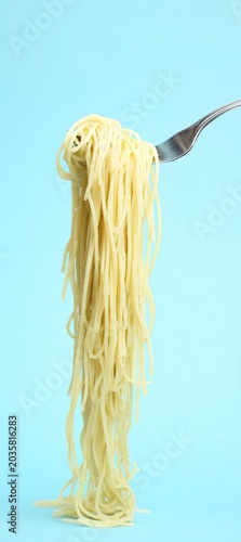 Vertical Spaghetti Noodles on Silver Fork with Light Blue Solid Background