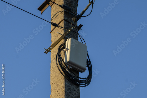 Wireless Communication Device Attached to a Utility Pole in a Clear Blue Sky During the Day