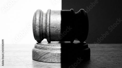 Justice Divided: A gavel rests on a split background of stark black and white, symbolizing the duality and complexity of law and judgment.