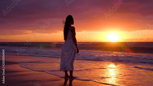 Woman watching beautiful sunset on a peaceful ocean beach