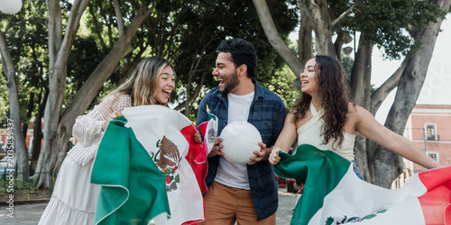 group of mexican soccer fans holding a soccer ball and national flag supporting to their sport team outdoors in Mexico city in Latin America
