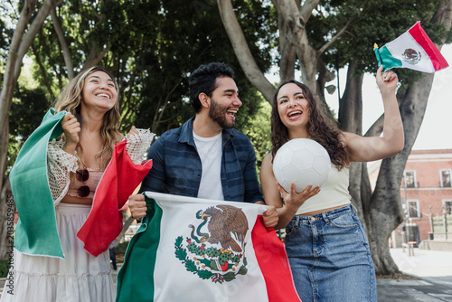 group of mexican soccer fans holding a soccer ball and national flag supporting to their sport team outdoors in Mexico city in Latin America