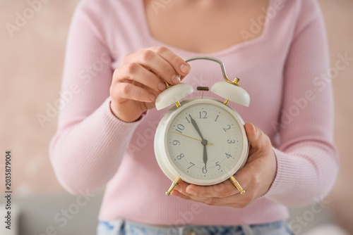 Photography Woman holding white alarm clock close up, morning routine and time management co