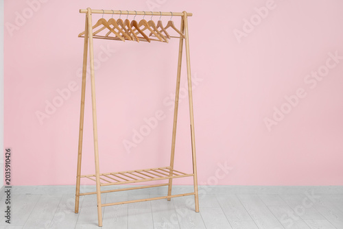 Photos Wooden rack with hangers near pink wall
