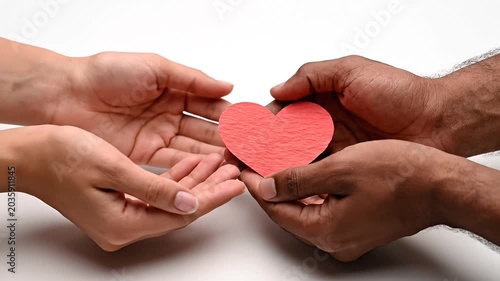Couple hands holding a red paper heart cutout.