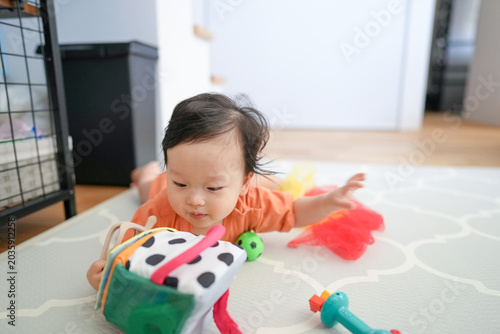 Фотография Little child plays with colorful toys on a patterned rug
