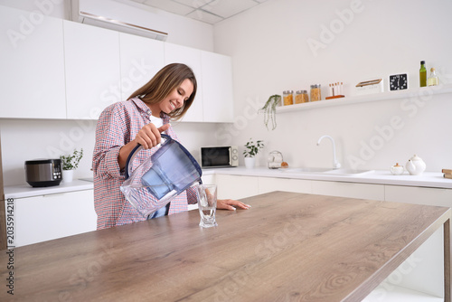 Young woman pouring water f...