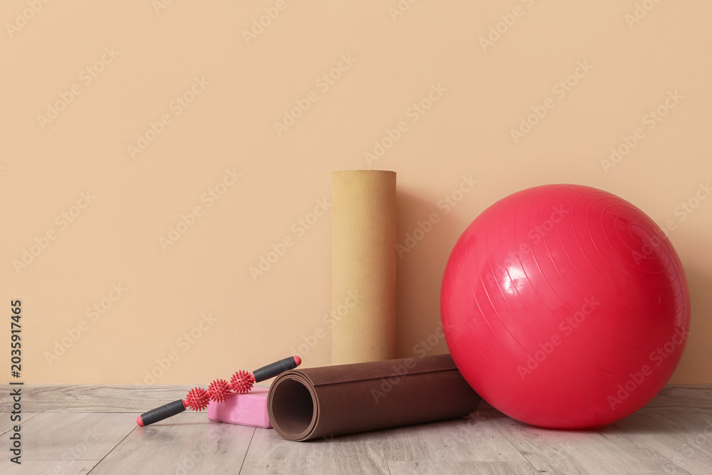 Naklejka premium Set of sports equipment with fitness ball on floor near color wall