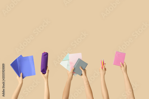 Fotografie Female hands with school supplies and copybook on beige background
