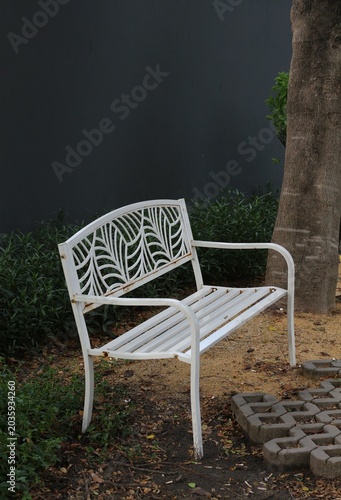Foto Ornate white metal garden bench with decorative leaf pattern on backrest