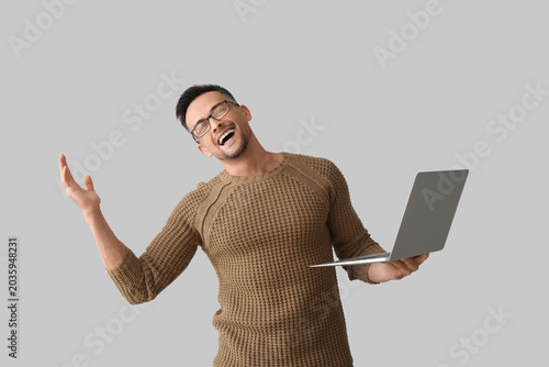 Happy young man with laptop...