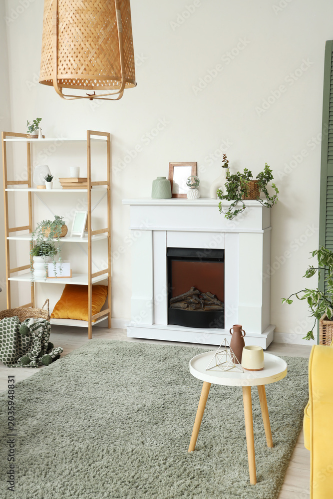 Fototapeta premium Interior of living room with electric fireplace, shelf unit and houseplants