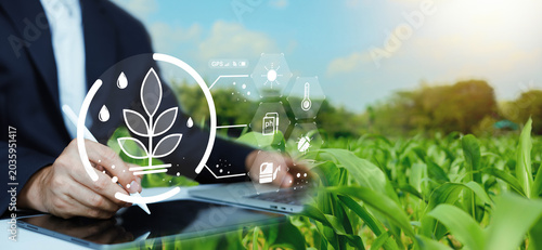 Foto Businessman using stylus pen on tablet in green crops field with smart agriculture icons, precision farming technology, sustainable agronomy and digital crop monitoring concept