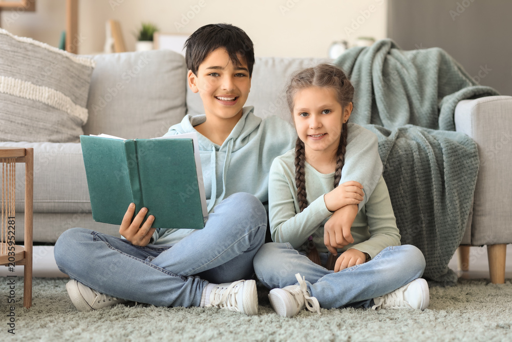 Fototapeta premium Little boy with his sister reading story at home