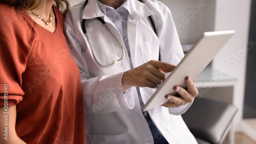 Canvas Print Close up shot of medical specialist using tablet consulting female patient, accessing digital health records, explains procedure results, treatment plan, prescribing medication