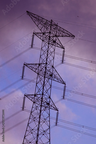 Close up silhouette of power cables piercing intense golden sun flare. Minimalist nature and industry backdrop for mental clarity, focusing therapy and sustainable resource grid