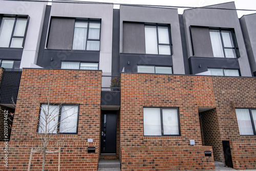 фотографія A contemporary multi-storey townhouse features a combination of brick on the lower levels and render on the upper floors in Melbourne