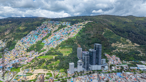 Obraz na plátně A vibrant urban landscape features colorful houses on a hillside beside contemporary skyscrapers in Bogotá, Colombia