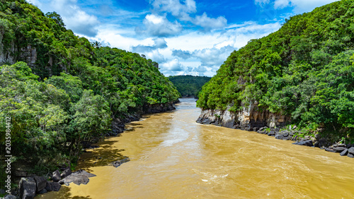 Photos The Guayabero River meanders through verdant hills under a blue sky, showcasing the rich biodiversity of the Colombian landscape