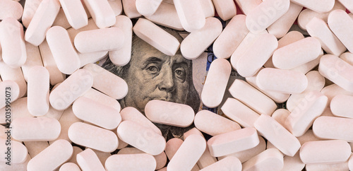 Bild auf Leinwand A fragment of a $100 bill with a portrait of Franklin and a pile of pills