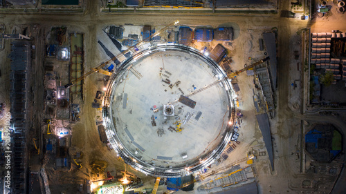 Foto Industrial Construction Site at Night: An aerial view captures the immense scale of an industrial construction site at night, with a large circular structure at its center