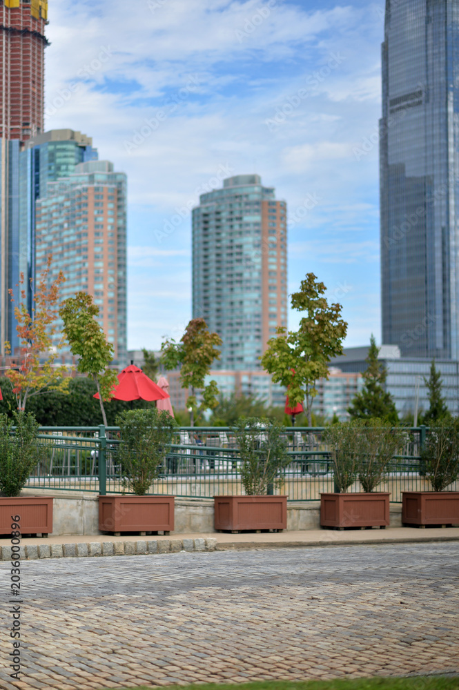 Obraz premium City Skyline Meets Tranquil Waters. Peaceful Promenade With Urban Skyline Backdrop new york