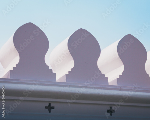 Grand Palace wall details in Bangkok, Thailand, showcasing traditional Thai architecture with white merlons shaped like lotus petals under a clear blue sky