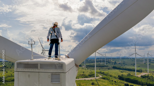 Tableau sur toile Wind Turbine Maintenance: A lone technician wearing a safety harness stands atop a wind turbine