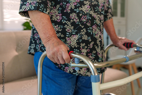 Elderly woman with aged hands gripping a walker, showing independent mobility and support for senior healthcare