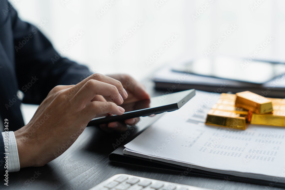 Fototapeta premium Asian businessman using smartphone trading gold bar on online market